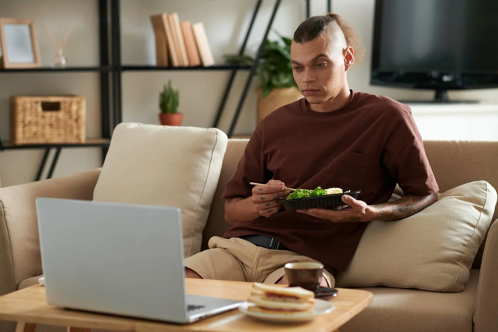  Man sitting on his couch watching his laptop and eating. Binge Eating Therapy in Austin, TX can help you cope with symptoms of binge eating disorder. Get Austin Eating Disorder treatment here with a skilled yoga therapist. 78703 |&nbsp;78704 |&nbsp;78731 