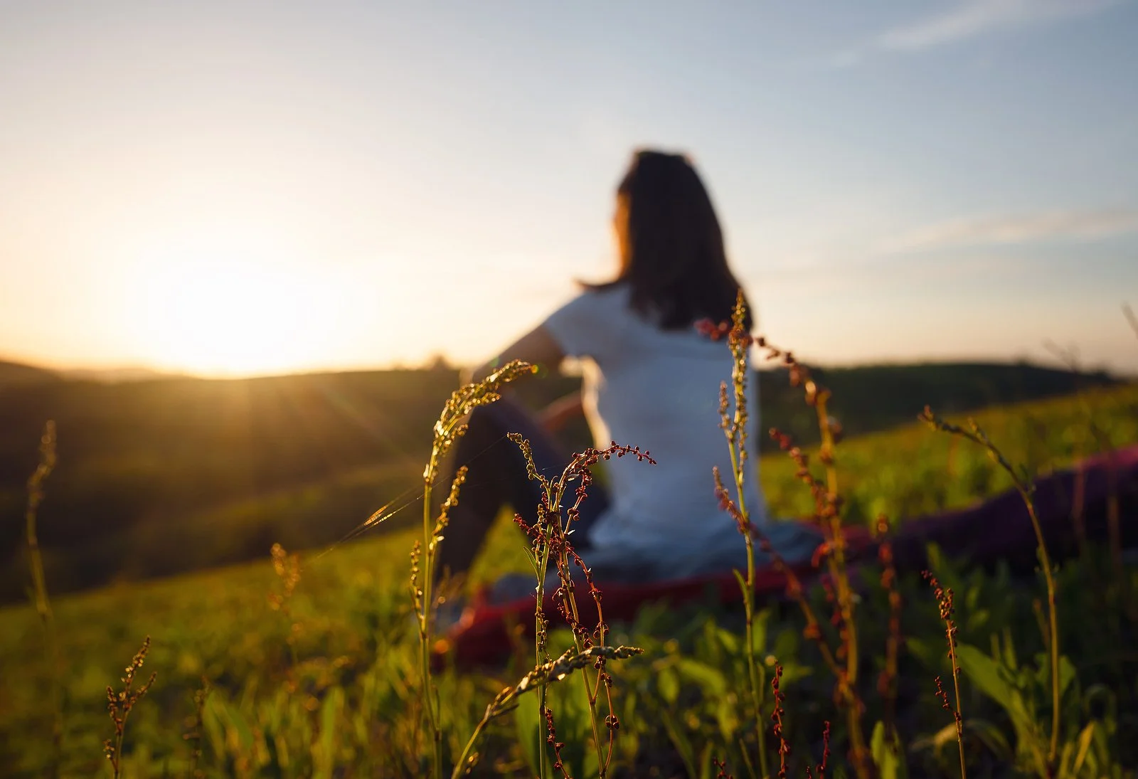  Woman sitting on a hill overlooking the sunrise. You can get online therapy in Texas from a Trauma therapist here. Learn about yoga for trauma therapy, and holistic and natural healing in Austin, TX. Trauma therapy in Texas can help you! 78701 | 78702 |&nbsp;78732 