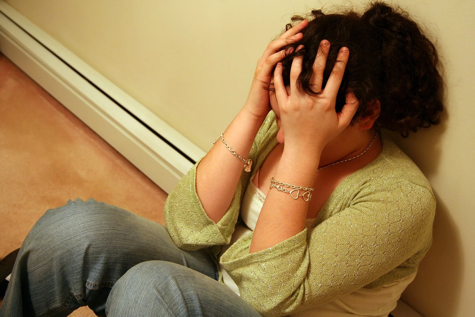  Woman sitting against the wall, holding her head in pain. Yoga for pain in Austin, TX might help for her care with therapy for chronic pain in Texas. Read on! | 78733 | 78730 | 78738  